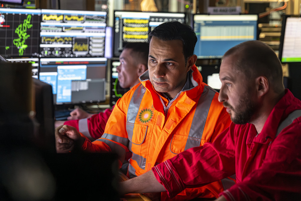 Three employees wearing gear working. 