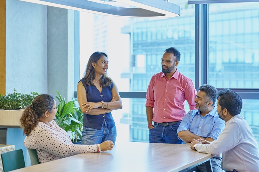 Five people sitting indoors having a conversation.