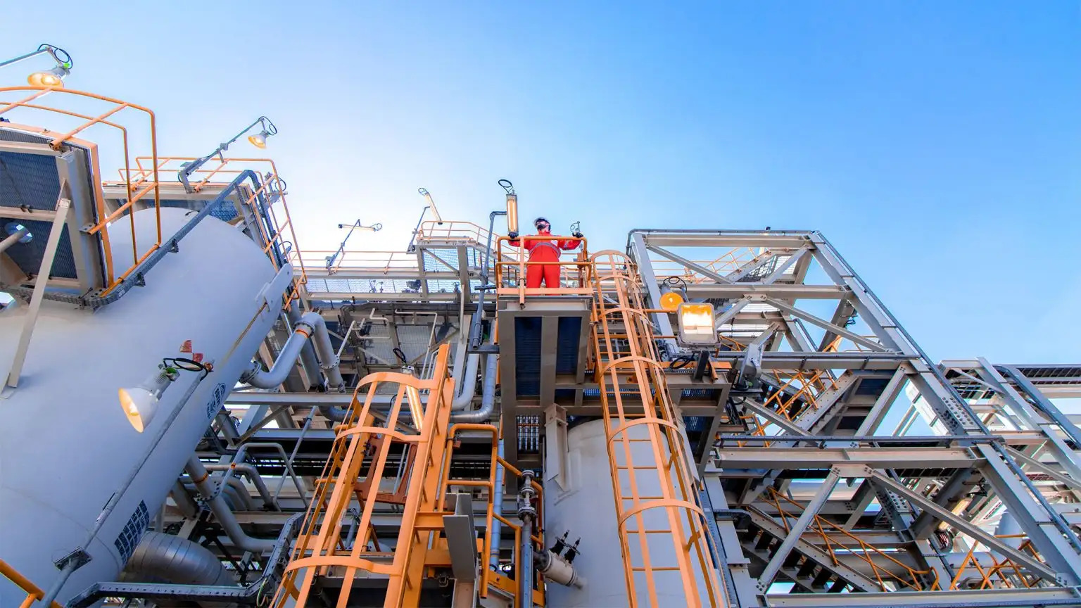 Workers standing on a platform surrounded by large industrial equipment and metal structures.