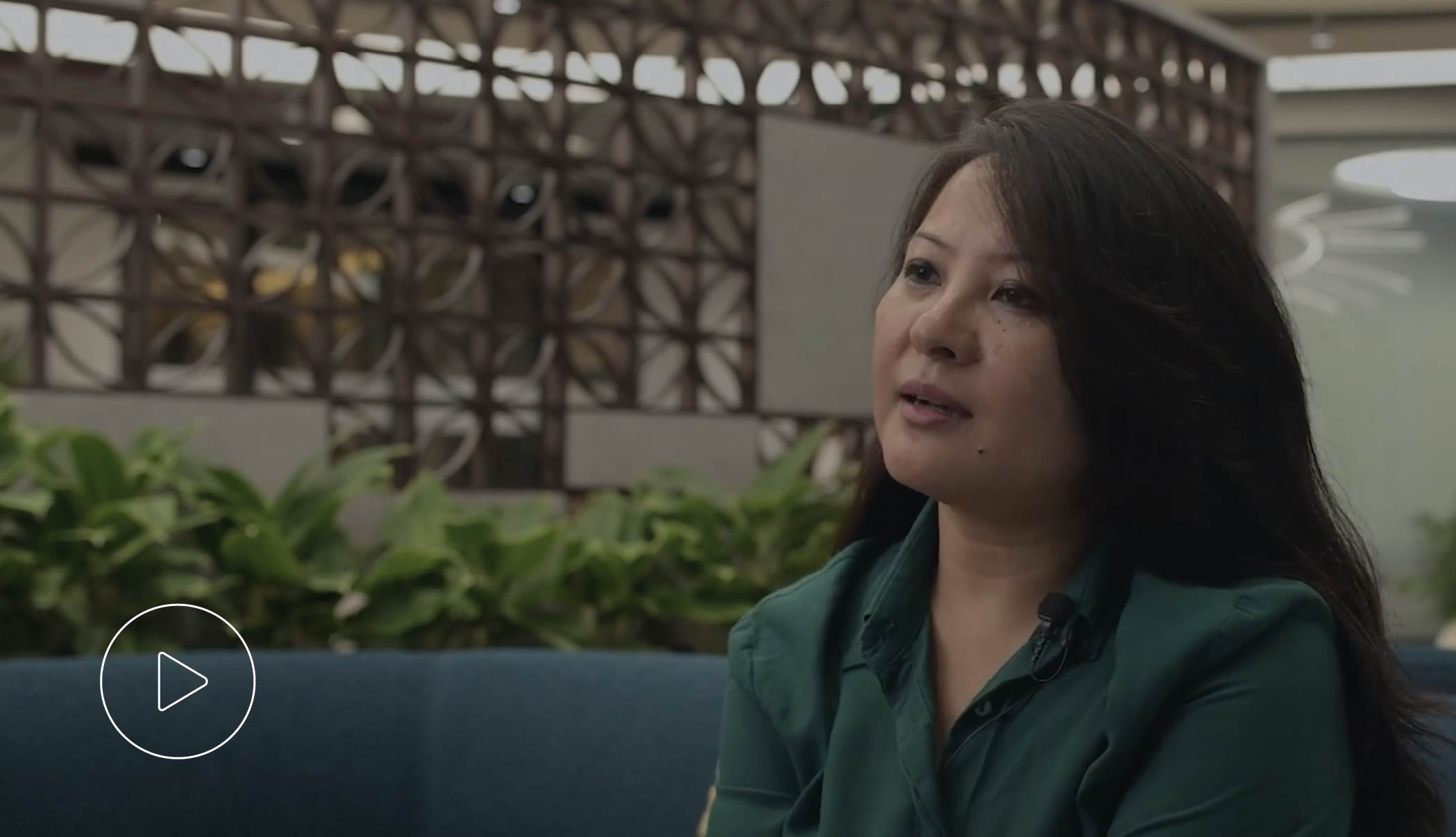 Binilla, Head of M&C AsPac and India Customer operations, is featured in a video still, seated on a blue sofa in an office setting.