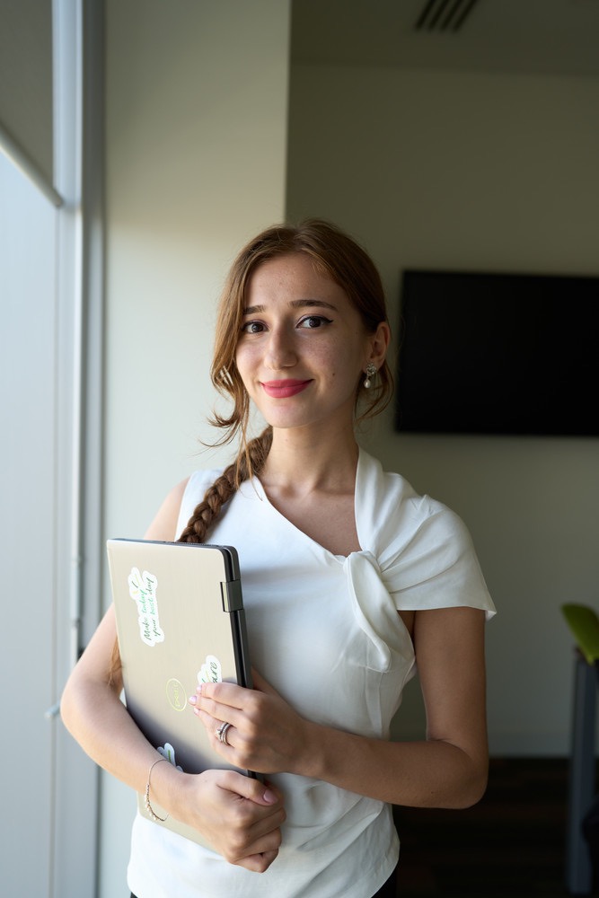 bp intern with laptop smiling in office, highlighting early careers, learning, and growth opportunities.