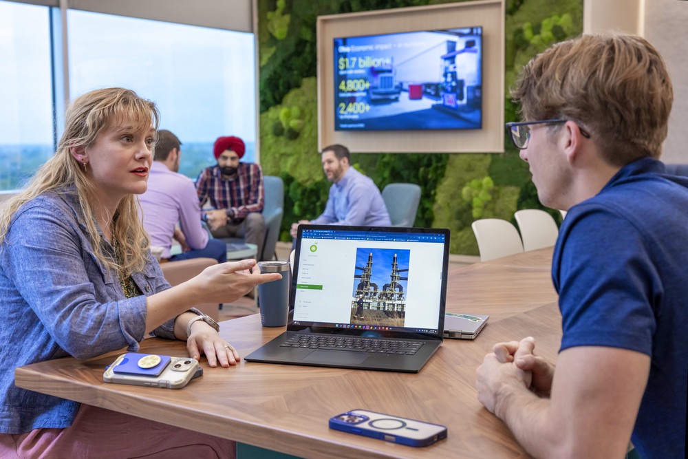 Team members having a discussion in an office with multiple computer monitors.