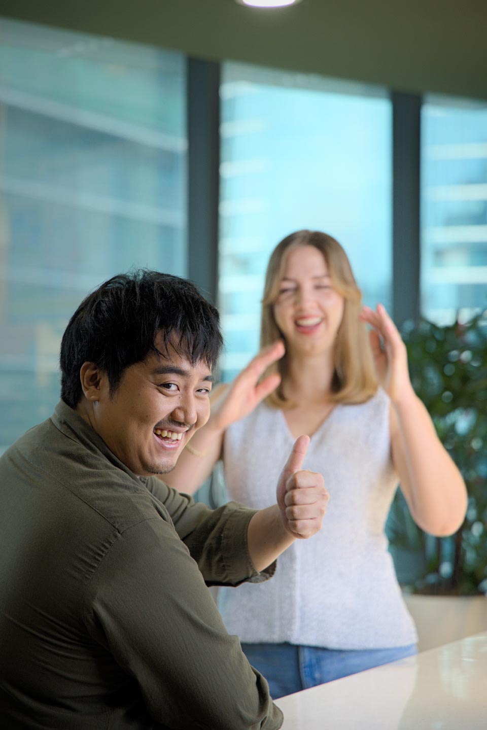 two employees smiling and talking in the office.