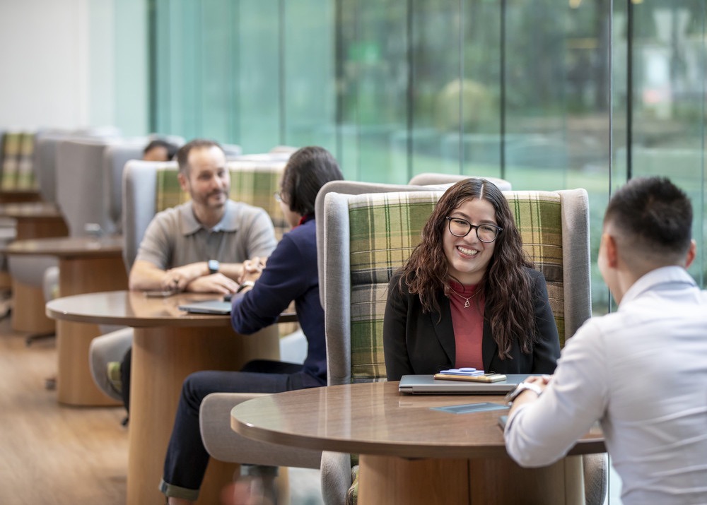 People having conversations at round tables in a bright modern office space.