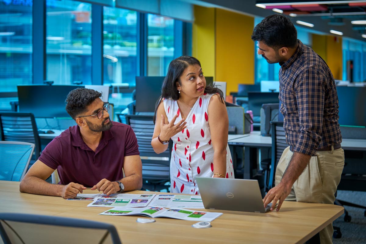 Three colleagues having a focused discussion in a modern office setting.