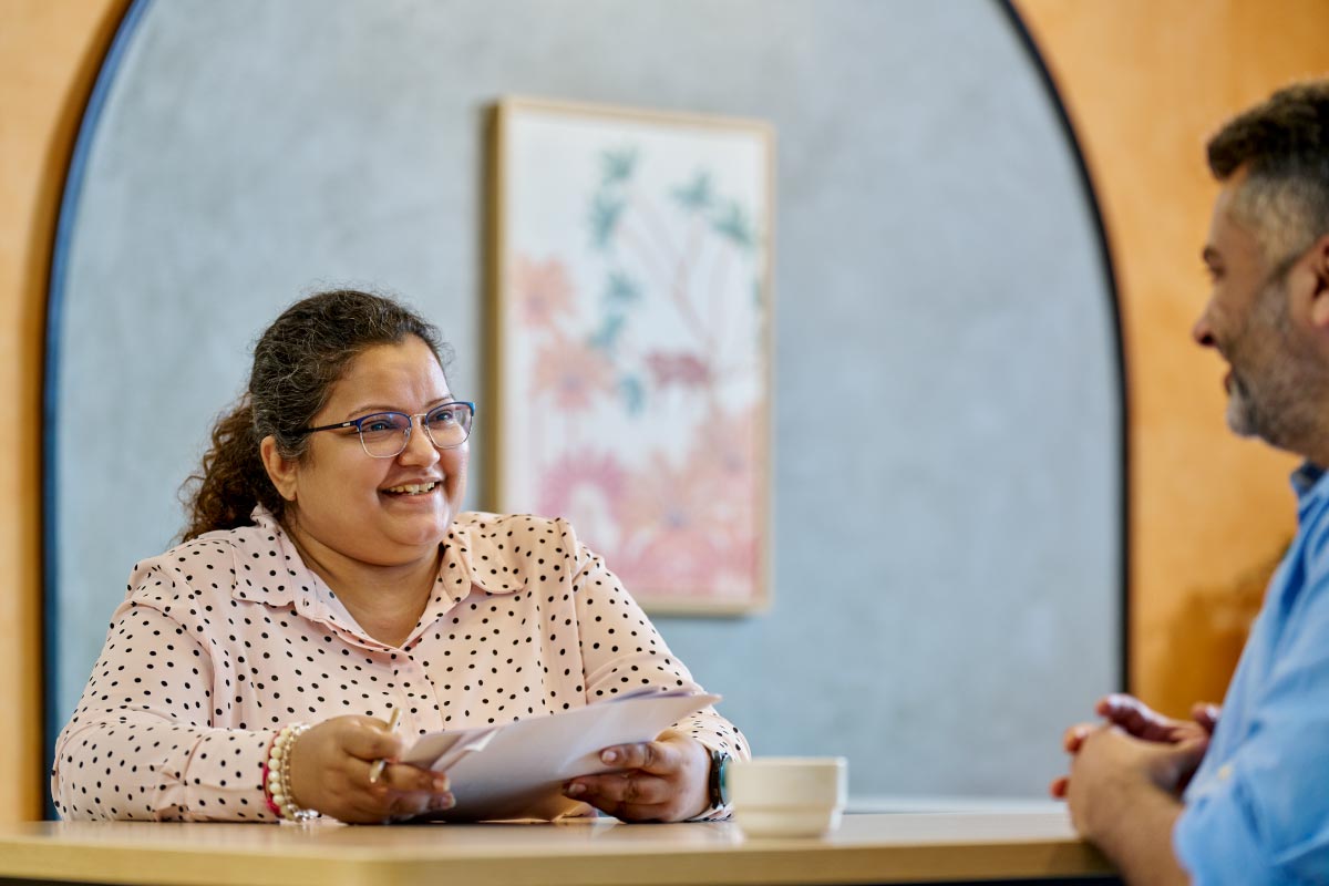 Two colleagues having a friendly conversation in an office setting.