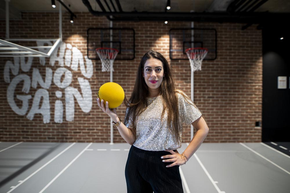 Female employee smiling and holding a ball.