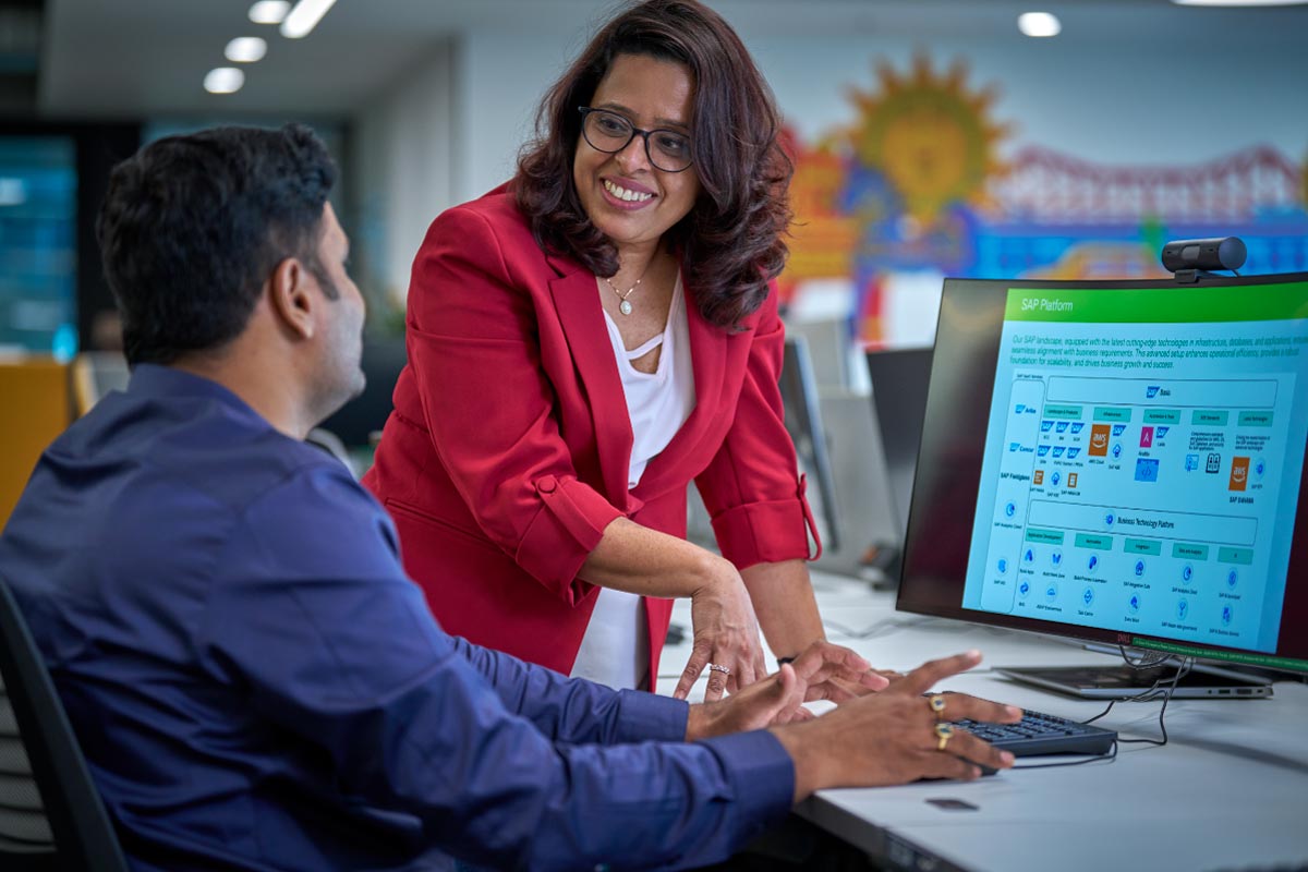 Colleagues collaborating at a computer in a modern office environment, highlighting teamwork and knowledge sharing.