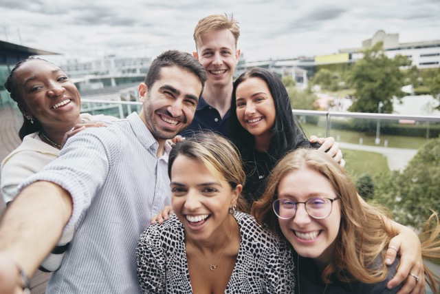 Group of diverse bp employees smiling and taking a selfie outdoors, showcasing inclusion, teamwork, and workplace culture.