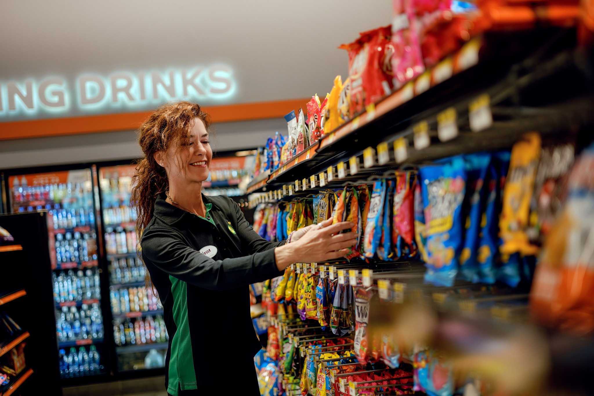 Store employee arranging snack bags on shelves.