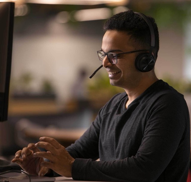 Smiling man wearing headset working at computer.