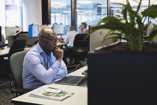 Focused bp employee in glasses working on a laptop at a desk in a modern office.