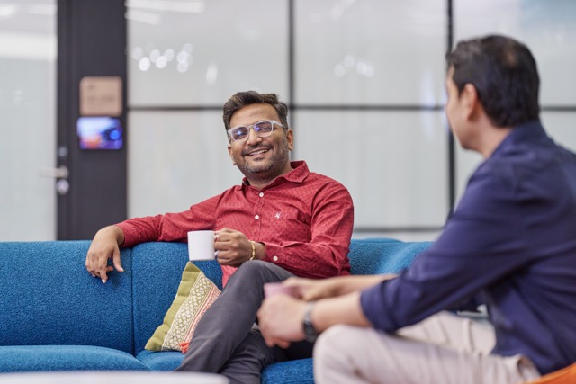 Two bp employees talking on office sofa, highlighting teamwork and company culture.