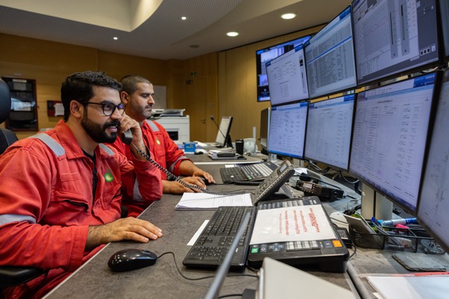 Two BP control room operators in red uniforms monitoring multiple screens and managing offshore oil and gas operations.