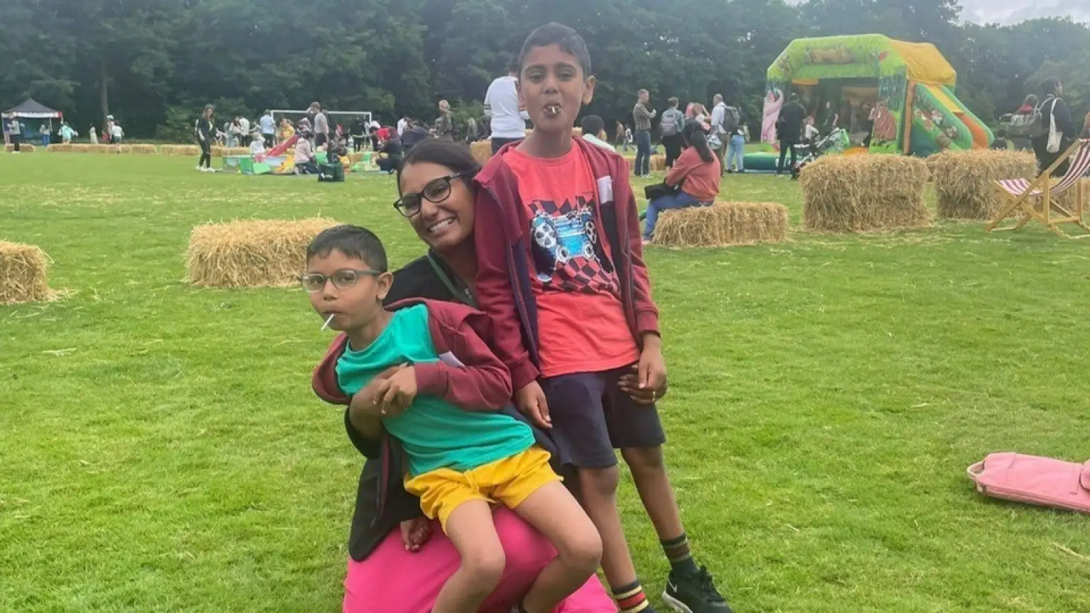 Three children smiling and playing at outdoor community event.