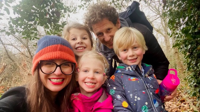 Family selfie outdoors with parents and three smiling children.