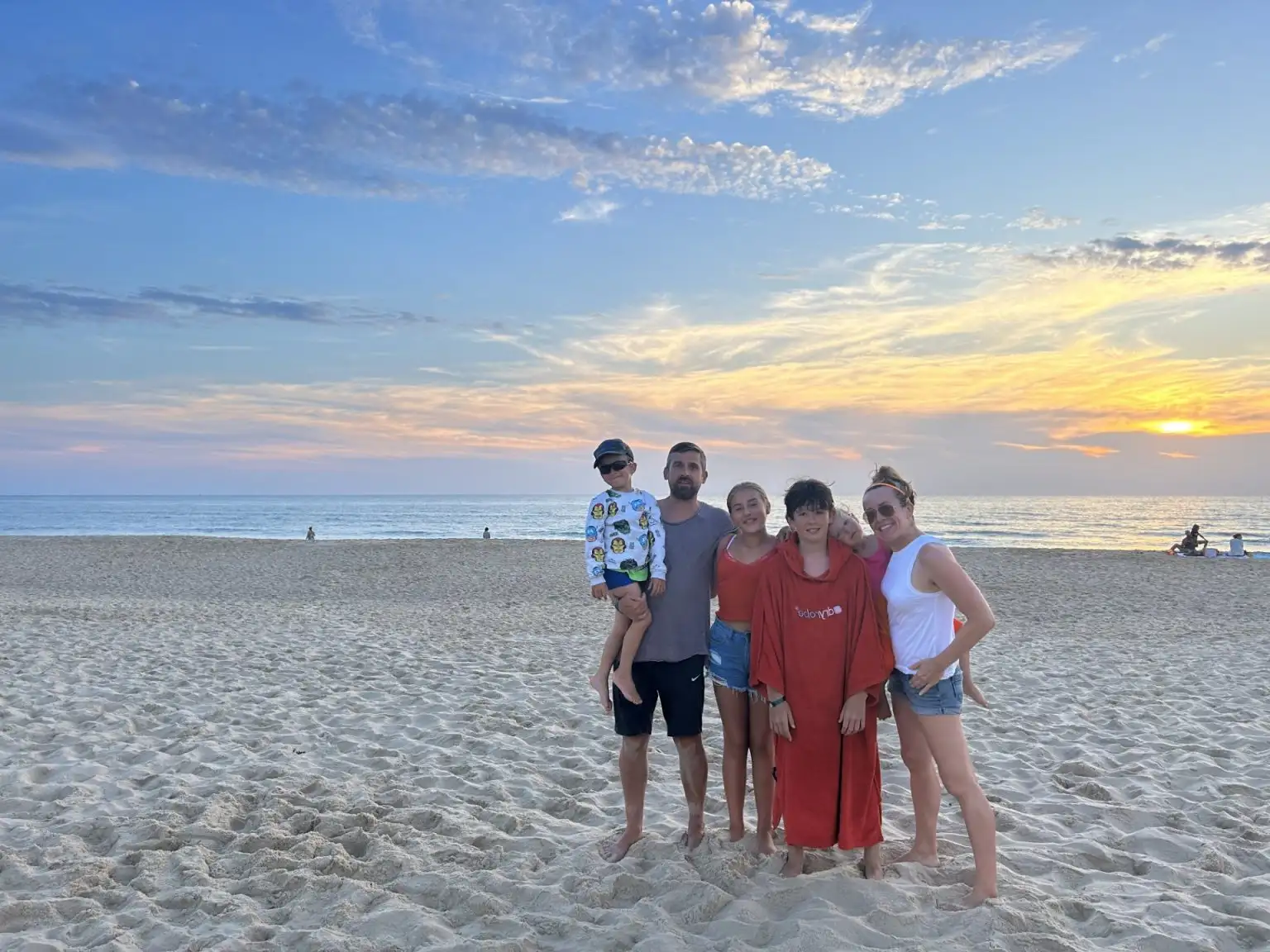 Family group photo on sandy beach at sunset.
