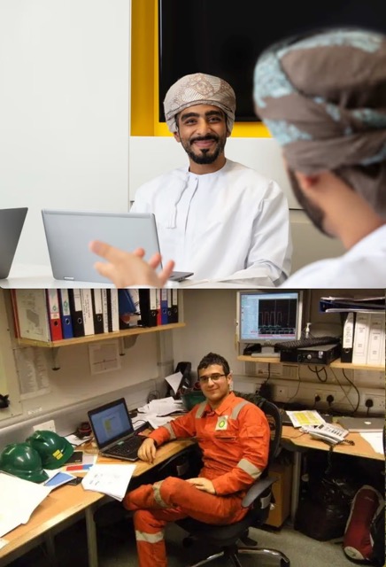 Worker in orange safety gear seated at computer in control room.