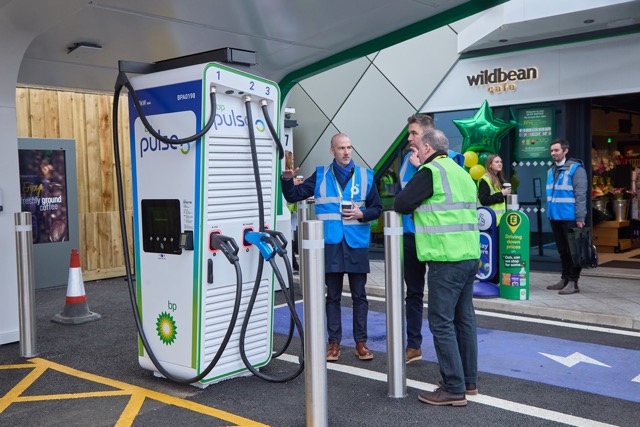 bp Pulse electric vehicle charging station with staff in high-visibility vests during EV infrastructure launch event.