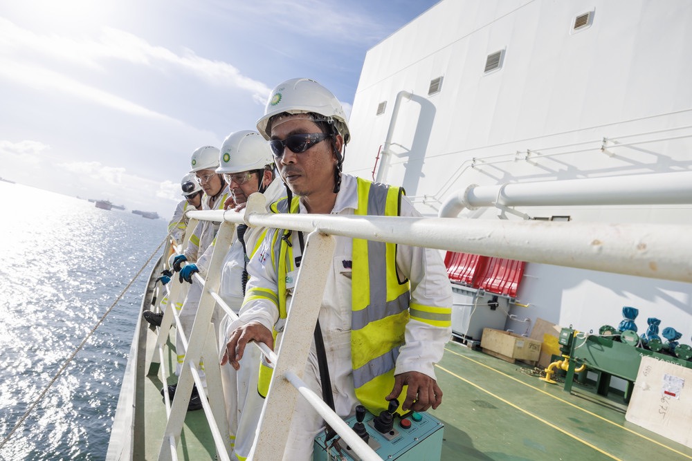 bp offshore workers in safety gear inspecting ship deck equipment, highlighting safety and reliability.