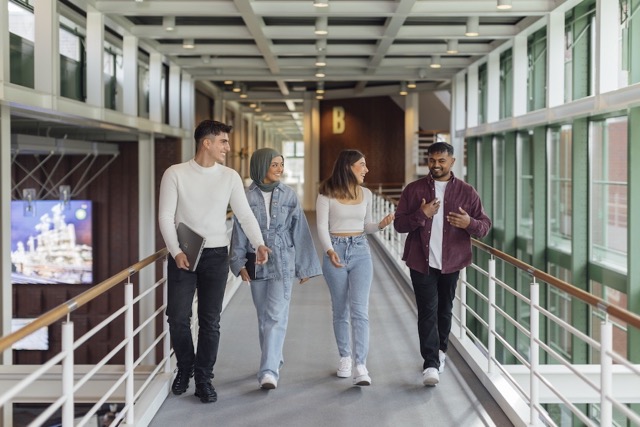 Diverse bp students walking together in a bright campus hallway, highlighting education and inclusion.