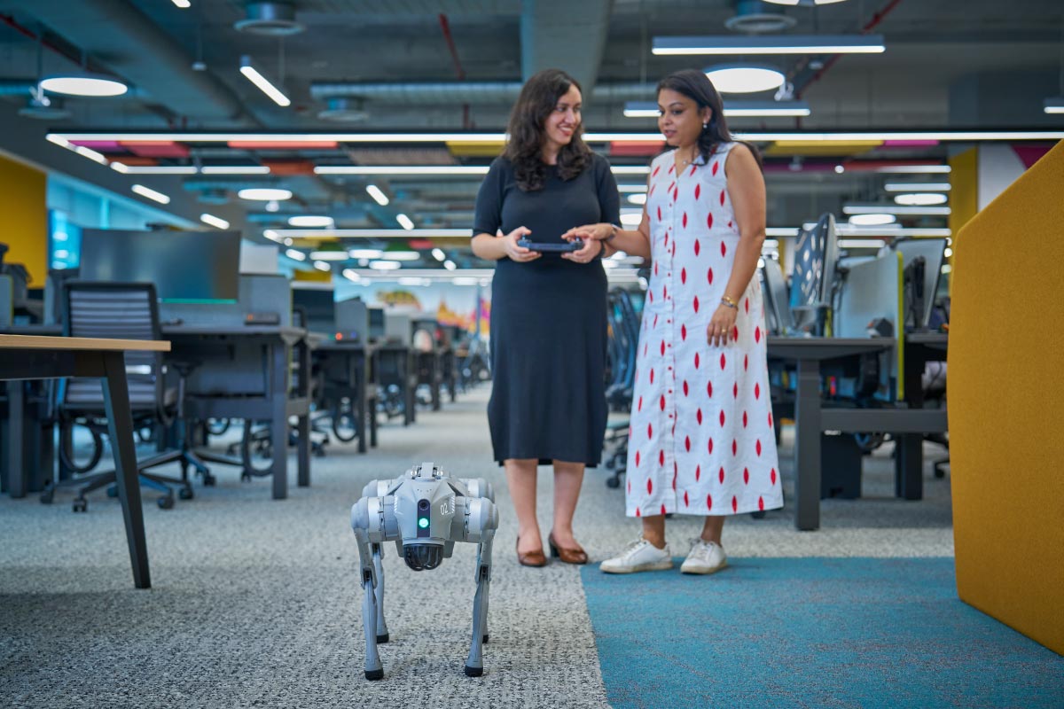 Two female employees walking through a modern office space while discussing work.
