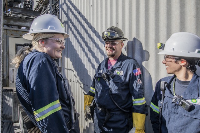Two workers in safety gear talking at an industrial site.