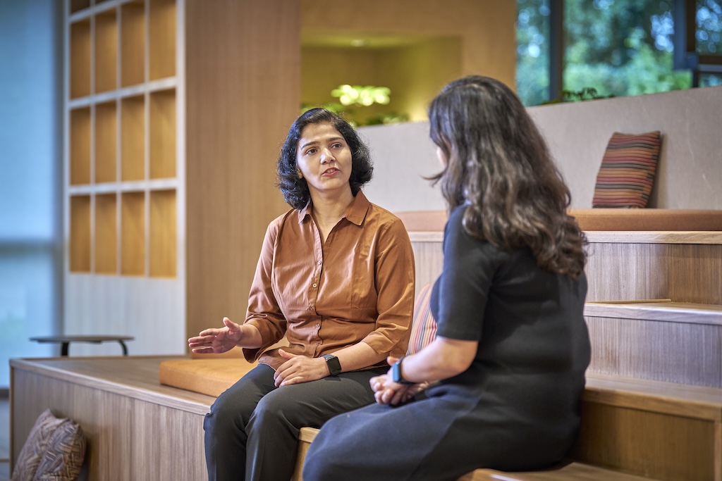 Two women sitting on wooden steps having a conversation.