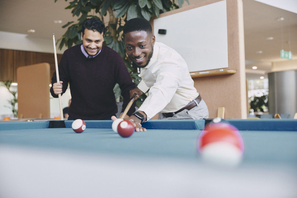 bp employees playing pool in office, highlighting collaboration, teamwork, and workplace culture.