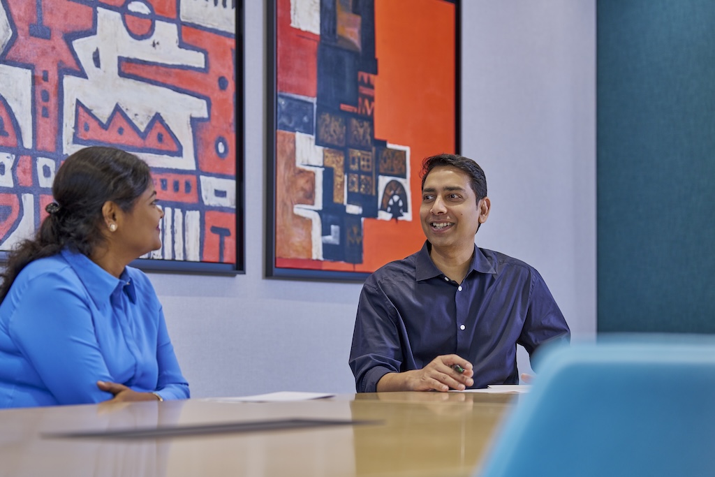 Two colleagues in a modern office having a discussion in front of colorful abstract artwork.