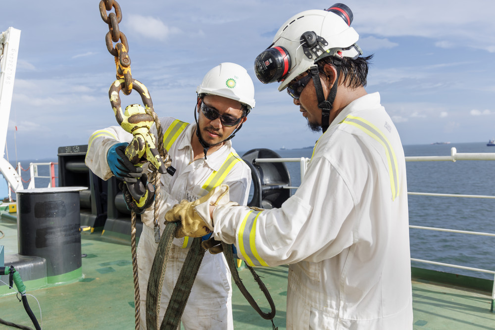 bp offshore workers in safety gear handling equipment on vessel, highlighting safety and reliability.